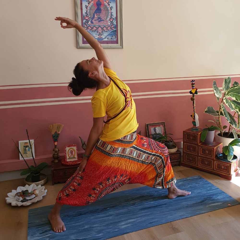 Cécile Taric en posture yoga et mudra, portant le t-shirt jaune et rouge YOGA & TSA LUNG en coton biologique de sa collection